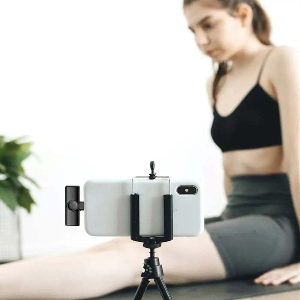 Draadloze microfoon bevestigd aan smartphone op statief voor video-opname met vrouw op achtergrond