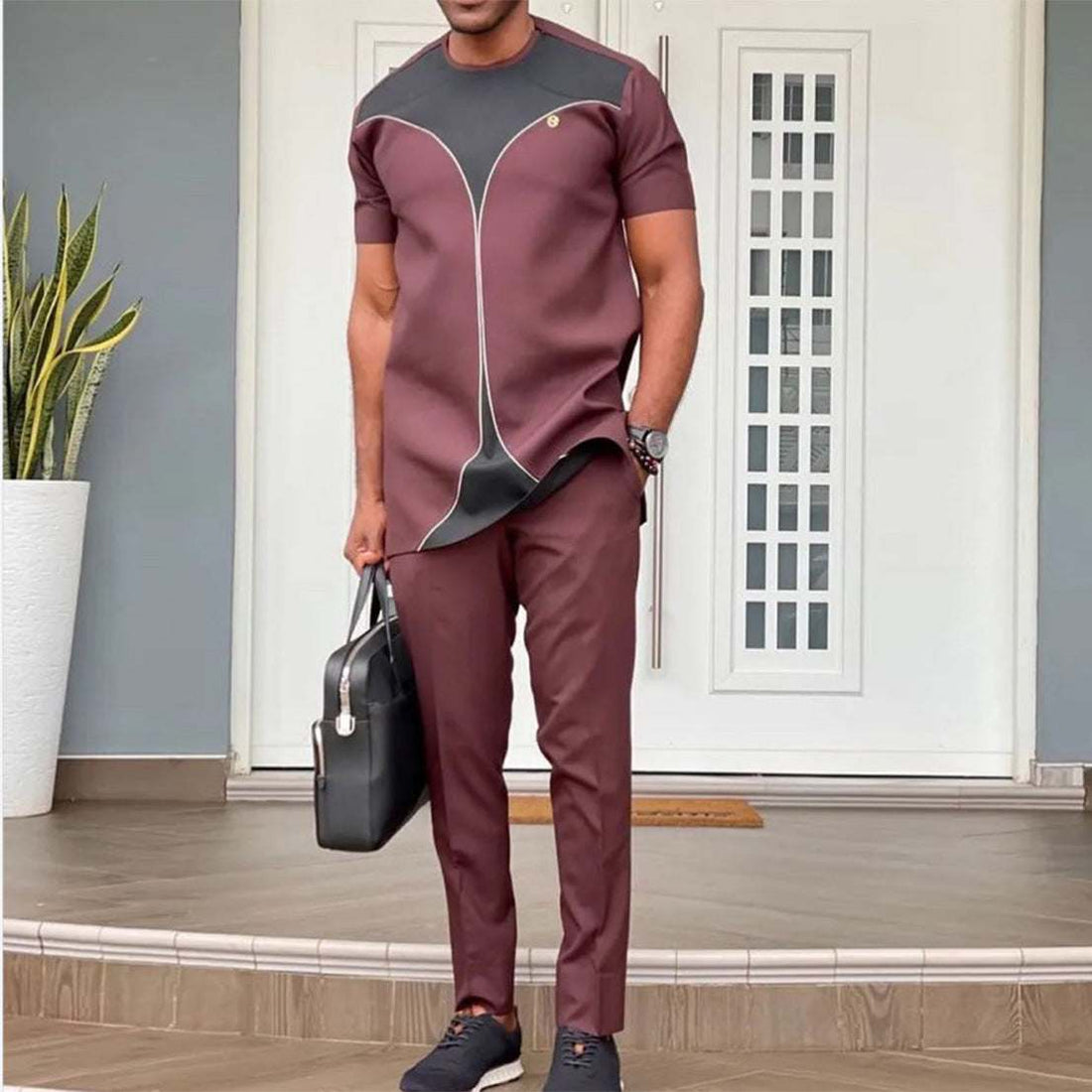 man wearing sfeervol mode zwart African style cotton suit with short sleeves and matching pants standing outdoors with black briefcase