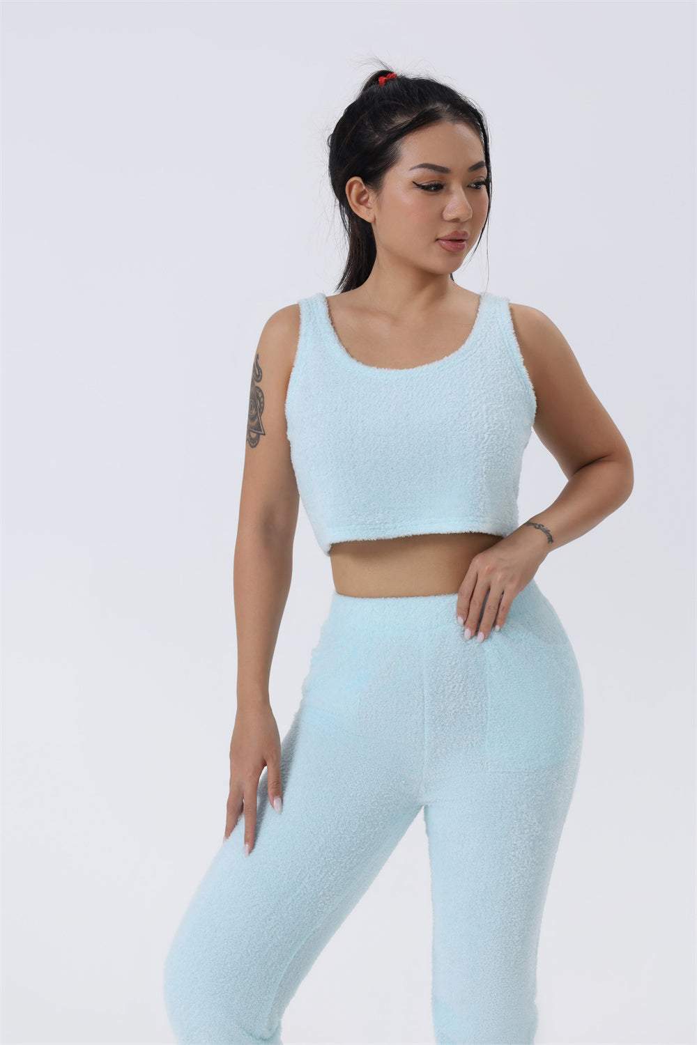 vrouwelijk model draagt zacht blauw 3-delige knit set bestaande uit crop top en broek