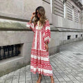 vrouw in zomerse dames vintage jurk met rood wit patroon lopend langs stenen muur