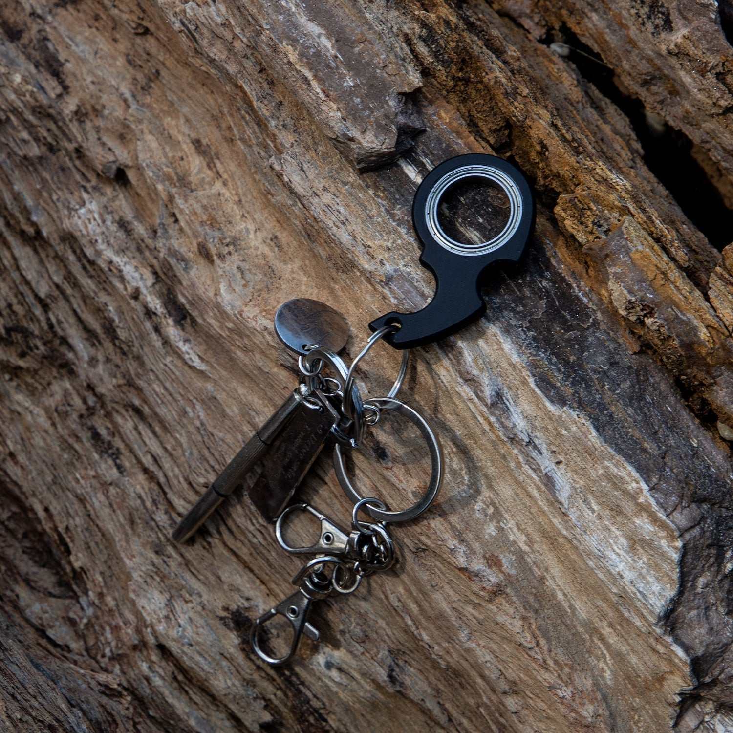 Zwarte sleutelhanger met Fidget Spinner speelgoed bevestigd op houten oppervlak, ideaal voor concentratie en ontspanning.