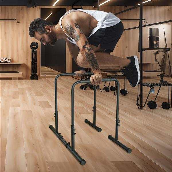 Man performing exercise on black Power Tower dip bars in gym with wooden floor and walls