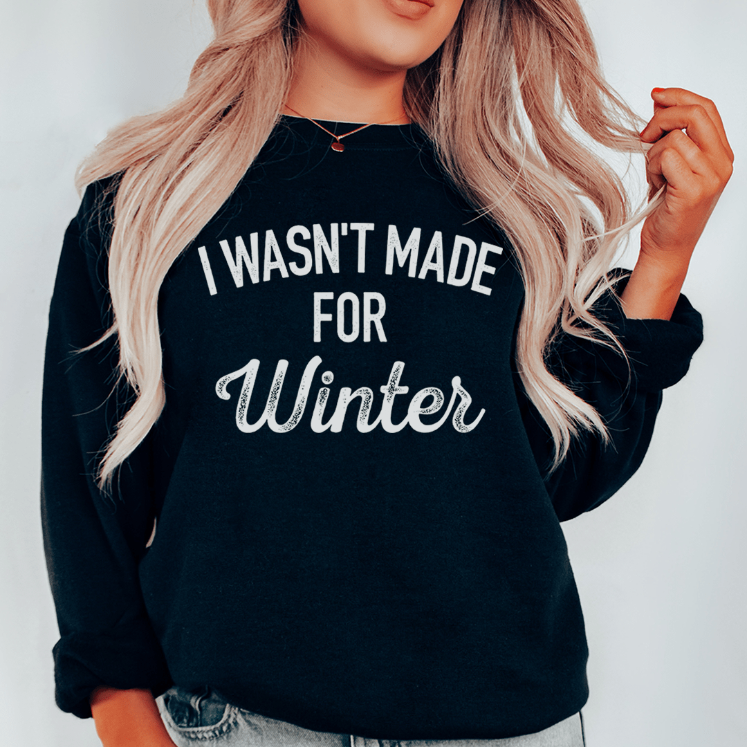 Black "I Wasn't Made For Winter" sweatshirt with cozy fleece lining and adjustable cuffs worn by blonde woman
